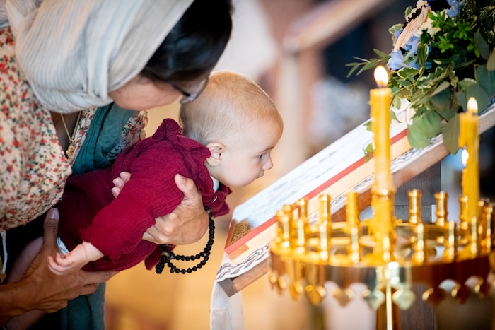 (Isaac Hale | Special to The Tribune) Four-month-old Theodora Gammo is held by her mother, Gabriela Gammo, as she kisses a painting of Jesus Christ while they and the congregation take part in veneration during a consecration service for St. Xenia Orthodox Church in Payson on Saturday, July 16, 2022.