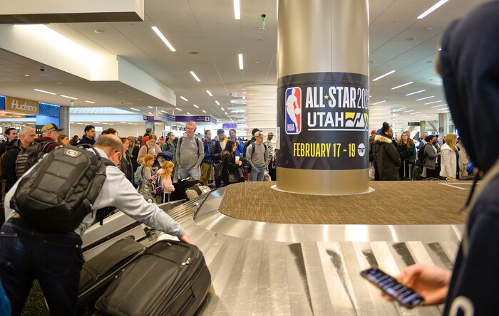 (Chris Samuels | The Salt Lake Tribune) Passengers collect baggage in front of All-Star Game signage at Salt Lake City International Airport, Friday, Feb. 17, 2023.
