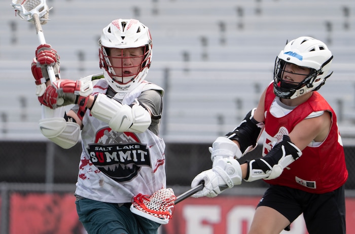 (Rick Egan | The Salt Lake Tribune)  Reilly Pearson-Ortolan (18) runs with the ball, as Pete Killilea 68 defends, in East youth lacrosse practice, on Wednesday, June 22, 2022.