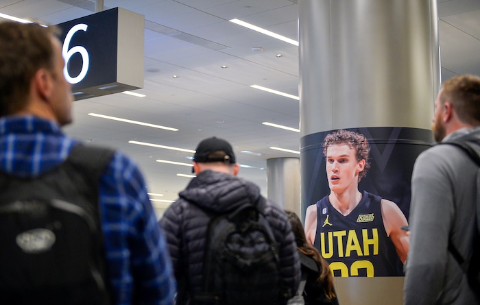 (Chris Samuels | The Salt Lake Tribune) Passengers collect baggage in front of a poster of Lauri Markkanen All-Star Game signage at Salt Lake City International Airport, Friday, Feb. 17, 2023.